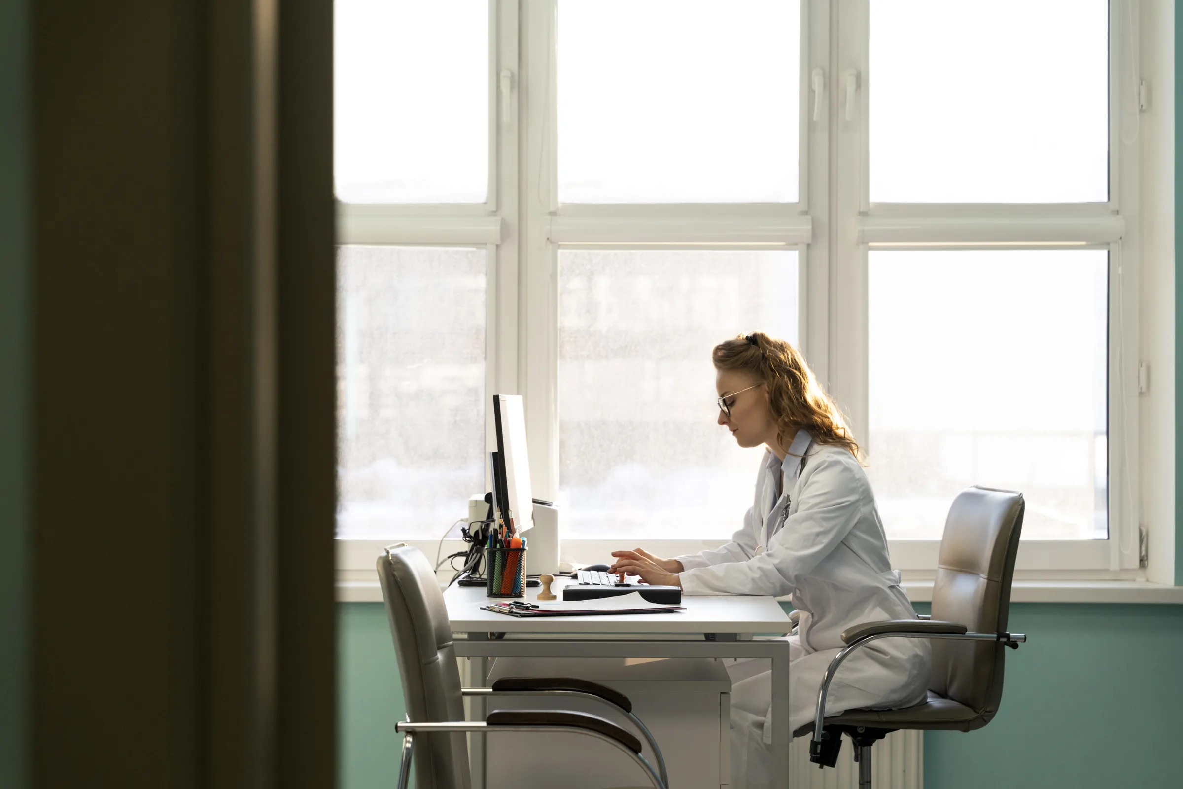 Ärztin arbeitet in einem hellen klinischen Büro am Computer